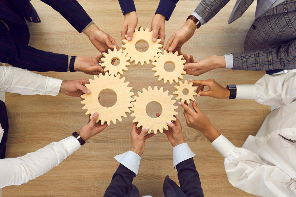 A group of hands holding wood cogs.